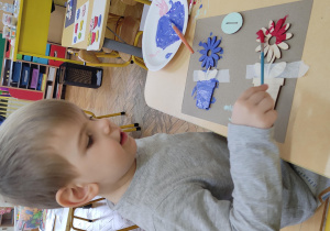 chłopiec malujący drewnianego kwiatka