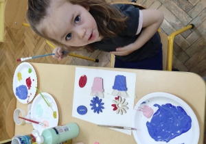 dziewczynka malująca drewnianego kwiatka farbami