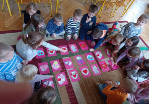 Na zdjęciu dzieci przyglądają się kartom do gry w Walentynkowe Memory