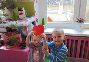 Na zdjęciu dzieci trzymają połączone połówki serca.