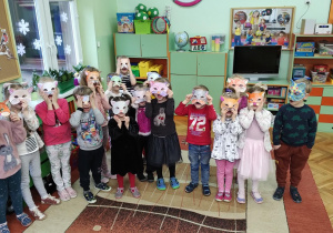 Zdjęcie grupowe dzieci z maskami kota na twarzach.