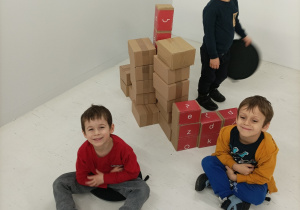 Na zdjęciu dzieci układają budowle z kartonowych pudełek