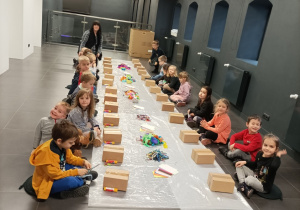 Na zdjęciu dzieci ozdabiają kartonowe pudełka