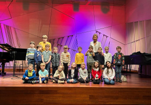 Dzieci stoją na estradzie w sali koncertowej