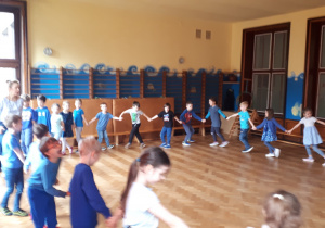Zdjęcie przedstawia dzieci podczas zabawy ruchowej na sali gimnastycznej