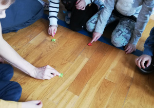 dzieci bawią się na podłodze papierowymi żabkami z origami