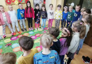 dzieci stoją naokoło kolorowej maty z numerkami