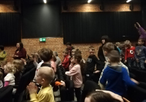 Dzieci na widowni z zaangażowaniem uczestniczą w spektaklu teatralnym