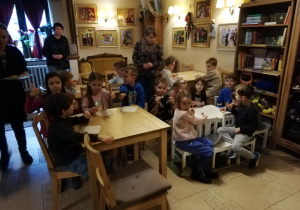 dzieci siedzą przy stolikach w Baśniowej Kawiarence czekając na przedstawienie