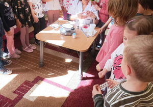 Na zdjęciu dzieci wraz z Panią oglądają etykietki i przygotowują się do sporządzenia kremu do rąk
