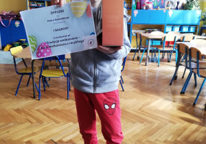 chłopiec prezentuje dyplom i nagrody, które zdobył na konkursie