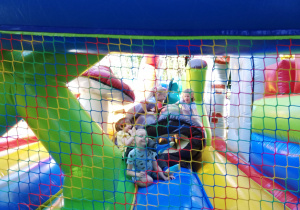 Na zdjęciu dzieci bawią się na dmuchańcach, skaczą i zjeżdżają na dmuchanej zjeżdżalni.