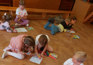 Dzieci w parach kolorują fragmenty układanki „Dzień Kropki” z bohaterami książeczki „Kropka”.
