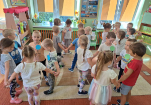 Dzieci biorą udział w zabawach ruchowych, mają przyklejone do ubrań kolorowe kropki.
