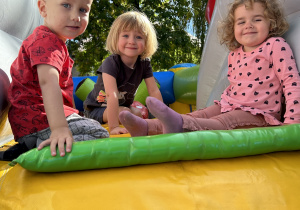 Na zdjęciu dzieci bawiące się na dmuchańcach w ogrodzie przedszkolnym.