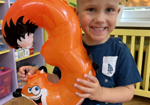 Na zdjęciu chłopiec z balonem w kształcie cyfry 3.