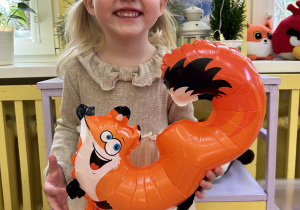 Na zdjęciu dziewczynka z balonem w kształcie cyfry 3.