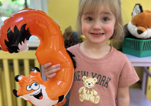 Na zdjęciu dziewczynka z balonem w kształcie cyfry 3.