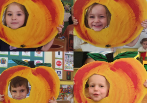 dzieci pozujące do zdjęcia z makietą przedstawiającą jabłko
