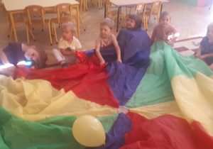 zdjęcie przedstawia dzieci z grupy ,,Misie” podczas zabawy z chustą animacyjną i balonami