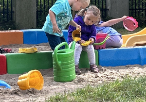 Na zdjęciu chłopiec i dziewczynka bawią się w piaskownicy