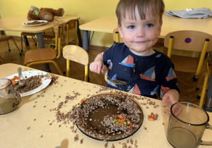 Na zdjęciu uśmiechnięty chłopiec przy stoliku podczas jedzenia obiadu.