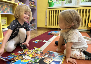 Na zdjęciu dwie dziewczynki układają puzzle na dywanie.