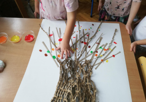 zdjecie pracy plastycznej " Jesienne drzewo", wykonanej na kartonie z materiałów recyklingowych oraz stempelkami zrobionymi paluszkami umoczonymi w kolorowej farbie przez dzieci