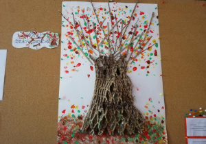 zdjecie pracy plastycznej " Jesienne drzewo", wykonanej na kartonie z materiałów recyklingowych oraz stempelkami zrobionymi paluszkami umoczonymi w kolorowej farbie przez dzieci