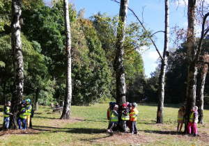 W parku – dzieci przytulają się do drzew.