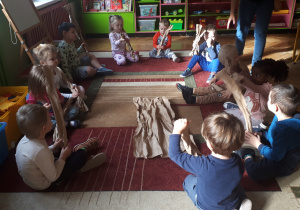 na zdjęciu dzieci z grupy ,,Misie” siedzące na dywanie i formujące gałęzie drzewa przy użyciu szarego papieru