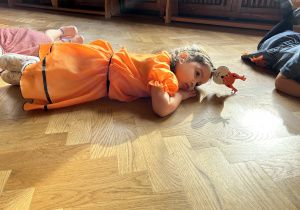 na zdjęciu dziewczynka leży na podłodze udając opadający z drzewa listek.