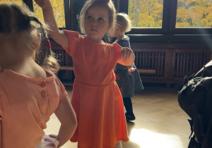 Na zdjęciu dziewczynka przebrana za wiewiórkę tańczy podczas zabawy muzycznej.