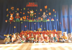 na zdjęciu dzieci z grupy ,,Misie” siedzące na tle dekoracji w Sali gimnastycznej