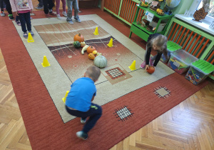 Na zdjęciu dzieci turlają slalomem dynie pomiędzy pachołkami.