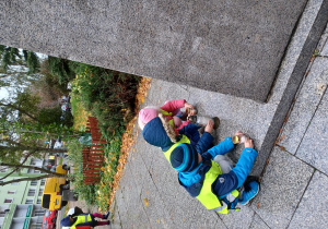na zdjęciu troje dzieci stawia zapalone znicze pod pomnikiem G. Narutowicza