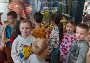Na zdjęciu dzieci stoją na tle akwarium
