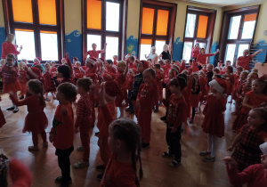 na zdjęciu dzieci w czerwonych, mikołajkowych strojach tańczące podczas zabawy mikołajkowej