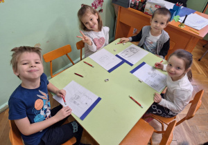 Na zdjęciu dzieci siedzą przy stolikach, projektują wnętrze swoich pokoi.