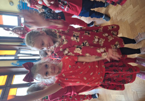 Na zdjęciu dwie dziewczynki ubrane na czerwono tańczą.