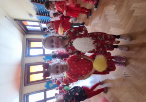 Na zdjęciu dwie dziewczynki ubrane na czerwono trzymają pompony i tańczą.
