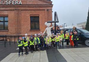 Na zdjęciu dzieci wraz z Paniami stoją przed budynkiem Monosfery.