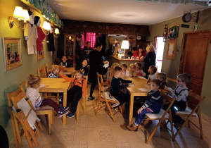 na zdjęciu: dzieci siedzą przy stolikach w Baśniowej Kawiarence - w tle na ścianach widać rekwizyty z różnych bajek