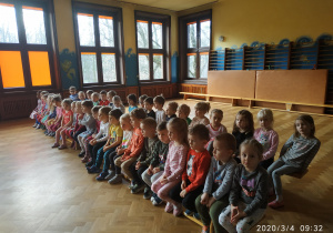 Dzieci z najmłodszych grup podczas słuchania bajek siedzące na ławeczkach