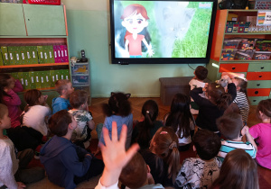 Dzieci oglądają film edukacyjny o kotach.