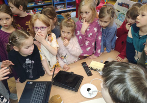 dzieci stojące wokół stolika podczas zabawy: rozpoznawanie urządzeń ekranowych.