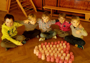 Dzieci siedzą na podłodze - przed nimi serce ułożone z różowych kubeczków