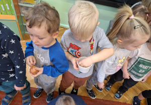 Na zdjęciu dzieci obserwują i dotykają cebule i nasiona owsa.