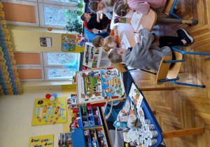 dzieci przy stolikach wypełniają kartę pracy - kolorują obrazki produktów ekologicznych