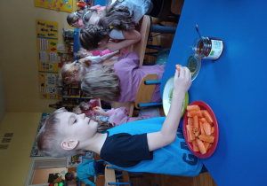 dzieci smakują ekologiczna marchewkę i ogórka z ekologicznym miodem
